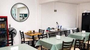 Un espace repas avec des tables rondes, des chaises, un distributeur automatique et un réfrigérateur.
