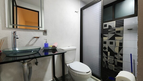 A bathroom with a glass sink, white toilet, and a shower area with a black door. - La Palma Co-living (Tecamac)