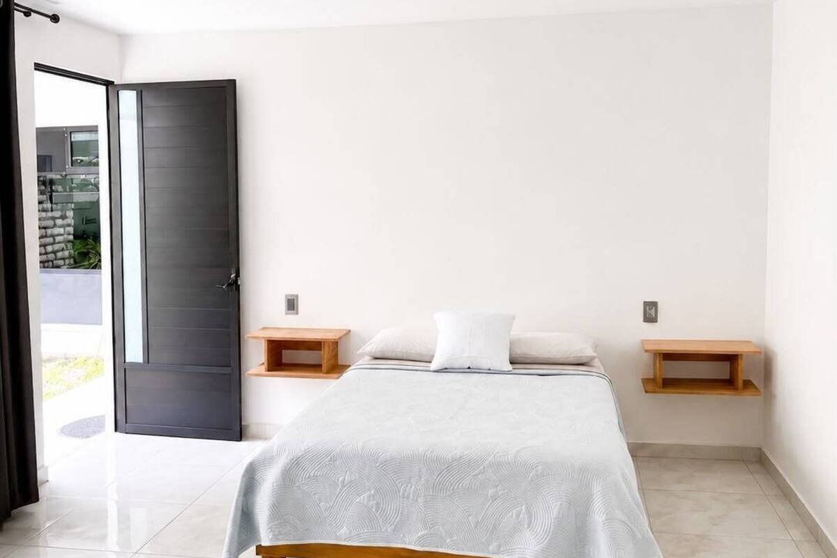 A modern bedroom with a bed, bedside tables, and a sliding door to a balcony.