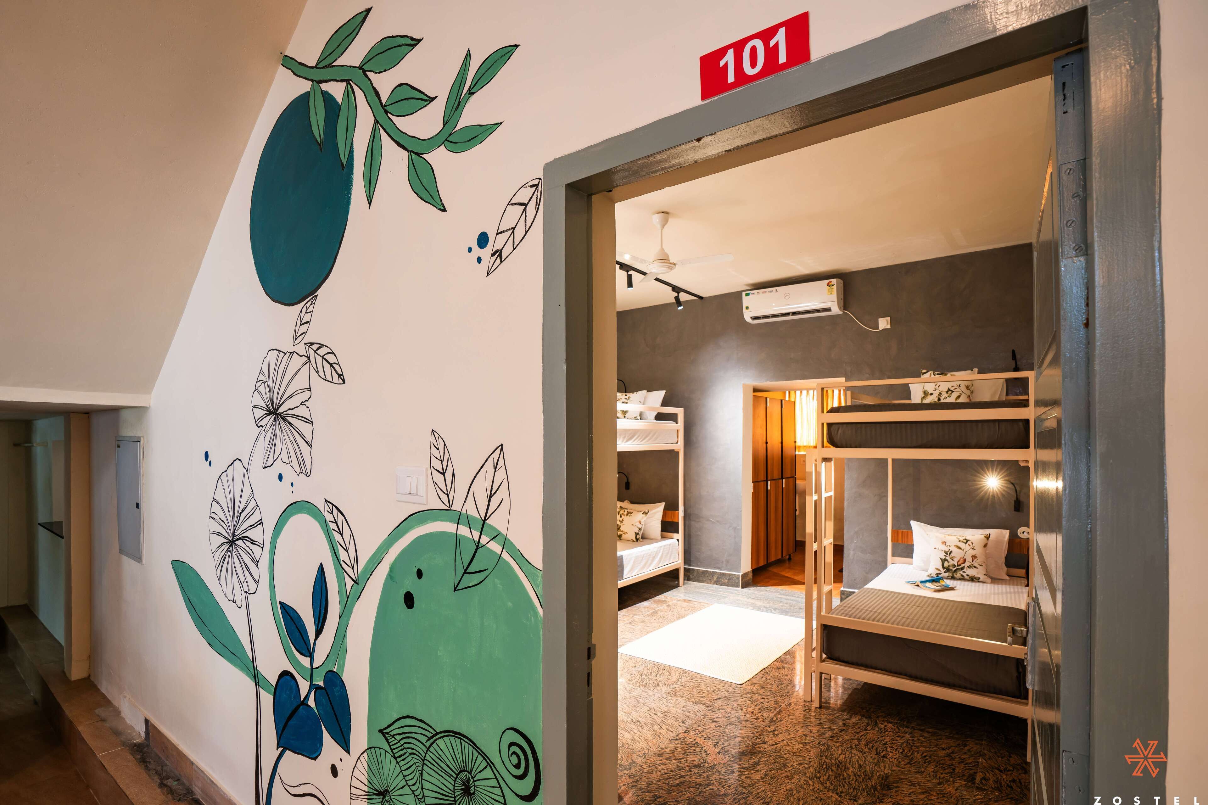 A hotel room with bunk beds, a wall mural, and a number sign indicating room 101.