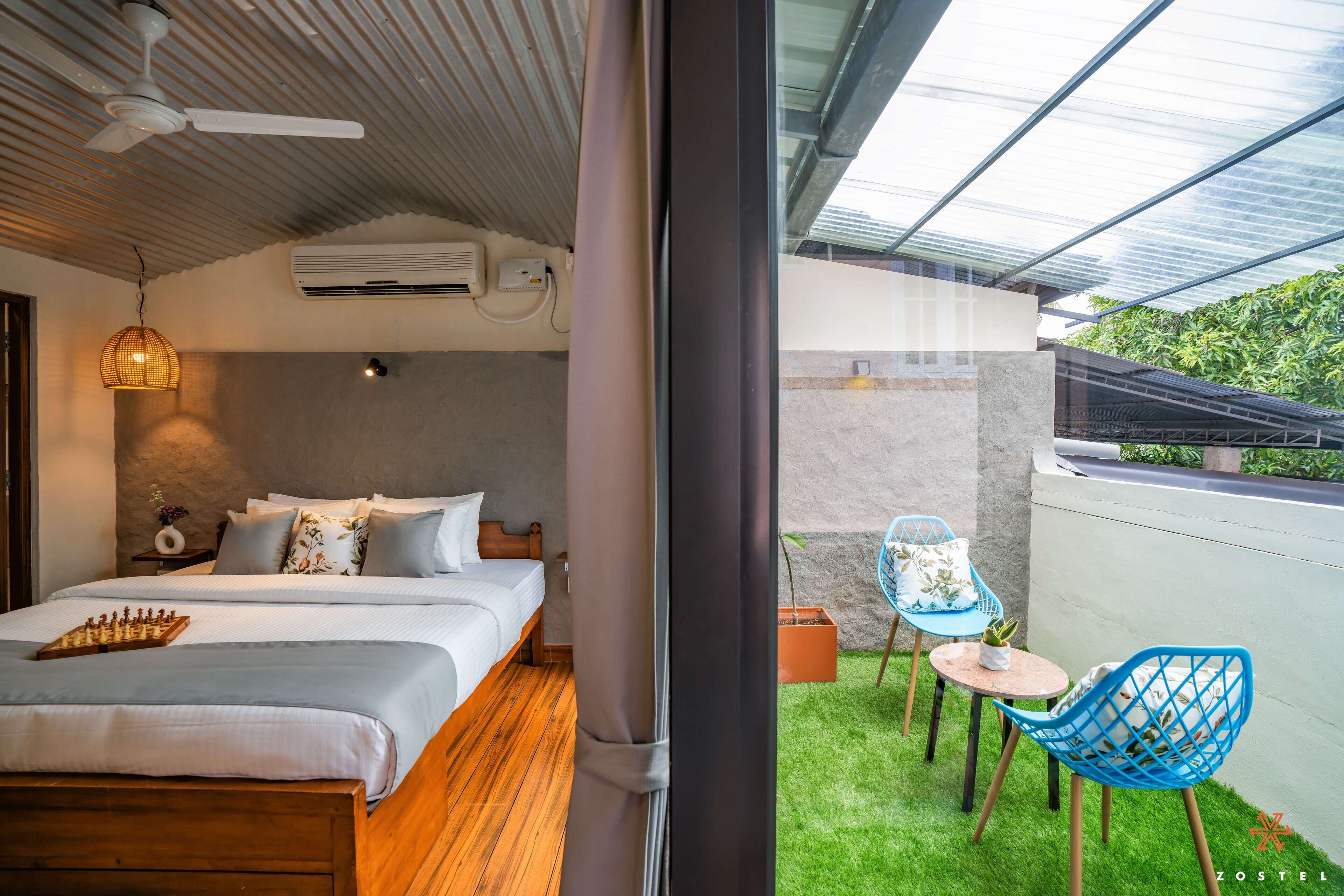Una habitación de hotel moderna con una cama, una pequeña mesa, una silla y un balcón con vistas a zonas verdes.