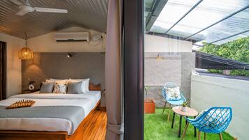 Una habitación de hotel moderna con una cama, una pequeña mesa, una silla y un balcón con vistas a zonas verdes.
