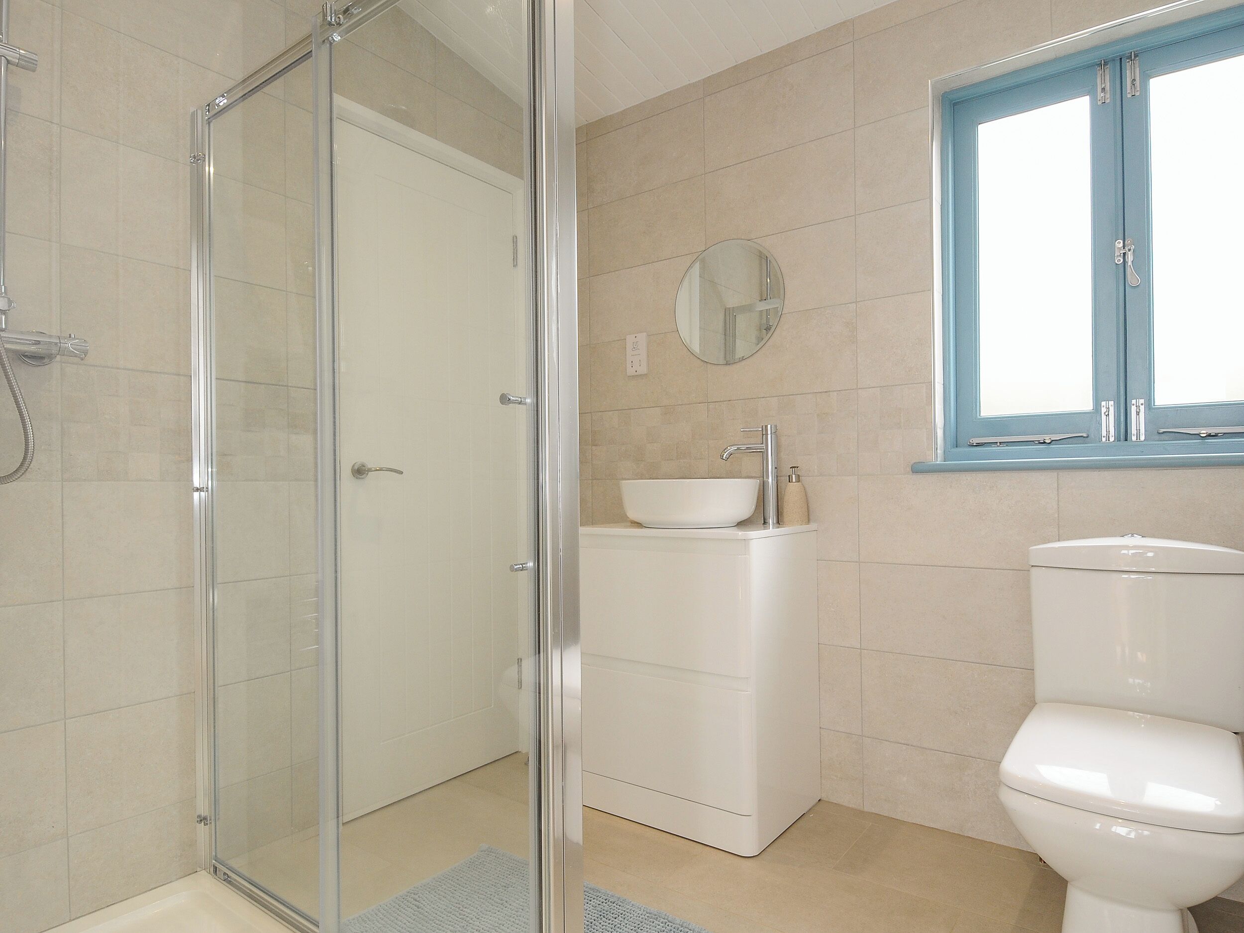 Une salle de bain avec une douche à parois de verre, un lavabo blanc et des toilettes.