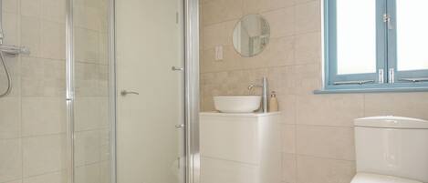 Une salle de bain avec une douche à parois de verre, un lavabo blanc et des toilettes.
