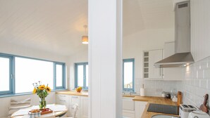 Una cucina luminosa con mobili bianchi, un piano di lavoro in legno e un davanzale blu.