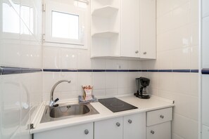 Eine kleine Küchenzeile mit Spüle, einer Kaffeemaschine und einem Fenster über der Spüle.