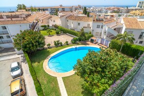 A residential area with a swimming pool surrounded by greenery and white buildings with tiled roofs. - Perdigon 325 Paradise by Casasol (Nerja)