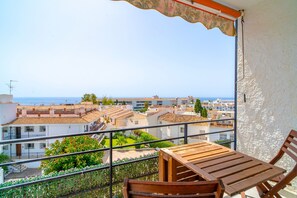 A balcony with a wooden table and chairs, overlooking a coastal town with terracotta-roofed buildings and a clear view of the sea. - Perdigon 325 Paradise by Casasol (Nerja)