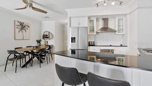 Uma cozinha moderna com armários brancos, uma ilha central e um ventilador de teto.