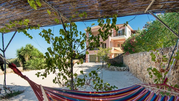 A hammock under a shaded area with a view of a building and a stone wall. - Villa Eleftheria: 4 bedrooms for up to 9 adults, pool and outstanding 180° views (Lakithra)