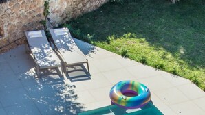 A swimming pool with a colorful inflatable ring, lounge chairs, and a stone wall in the background. - Villa Eleftheria: 4 bedrooms for up to 9 adults, pool and outstanding 180° views (Lakithra)