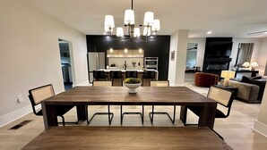 Een moderne eethoek met een grote houten tafel, stoelen en een decoratieve schaal in het midden.