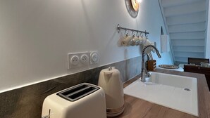 Moderni keittiö, jossa on kaksi seinään kiinnitettyä valaisinta, puinen työtaso, leivänpaahdin, vedenkeitin ja pesuallas.