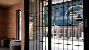 Ein modernes Interieur mit einer großen Glasdoor, einer Bank und einer Wand mit einer strukturierten Oberfläche.