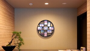 Ein Empfangsschalter im modernen Design, eine Wandcollage mit Fotos und ein Bonsai-Baum.