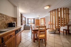 Une cuisine avec des meubles de rangement en bois, une table à manger et un escalier.