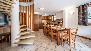 Una cocina moderna con armarios de madera, una mesa de comedor con sillas y una escalera con escalones de madera.