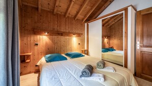 Una habitación con paneles de madera, una cama, almohadas, un espejo y una puerta.