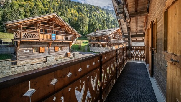 Una cabaña de madera con balcón que da a un paisaje montañoso.