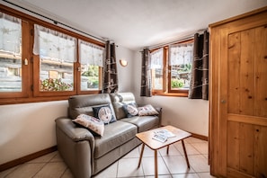 Une pièce chaleureuse avec un canapé en cuir, une table en bois et une vue dégagée grâce à de grandes fenêtres.