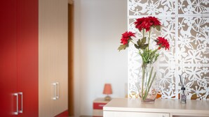 Ein Zimmer mit einem roten Kleiderschrank, einem weißen Schrank und einer weißen Dekorationstafel mit floralem Muster.