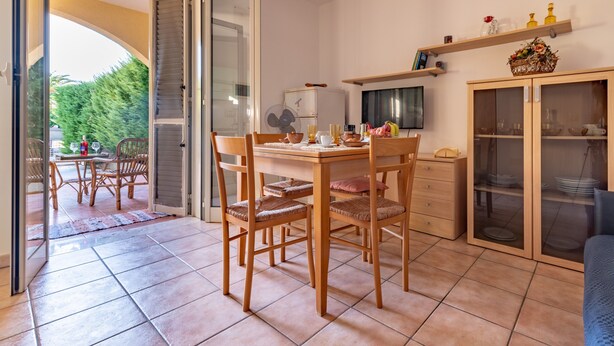Een eethoek met een tafel, stoelen, een televisie en een kast met glazen deuren.