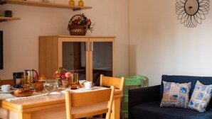 Een eethoek met een houten tafel, stoelen, een kast en een bank met gestreepte kussens.