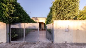 Een poort met een metalen hek, een betonnen muur en een betegelde vloer.