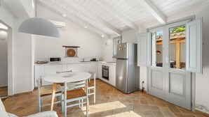 A modern kitchen with white cabinetry, a stainless steel refrigerator, and a dining area with a white table and chairs. - Holiday Home 'La Casetta' with Private Terrace, Wi-Fi and Air Conditioning (Giba)