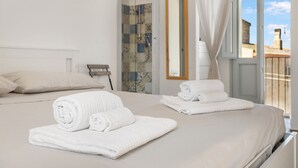 A hotel room with a bed, two rolled towels, a shower, a bathroom mirror, and a view of the outside. - Holiday Home 'La Casetta' with Private Terrace, Wi-Fi and Air Conditioning (Giba)