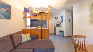 A compact living space with a kitchenette, a sofa, a dining table, and a chair.