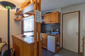 A compact kitchen with wooden cabinets, a small countertop, and a refrigerator.
