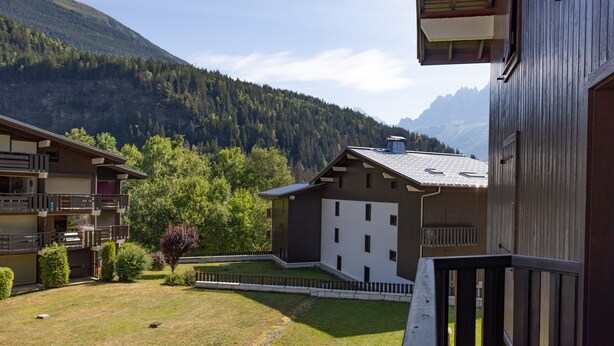 A building with a balcony, a fenced yard, and a mountain backdrop.