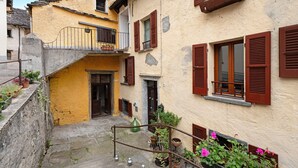 A narrow stairway leading to a building with a yellow facade, wooden shutters, and potted plants. - Apartment "Casa del Sole" with Mountain View & Wi-Fi (Toceno)