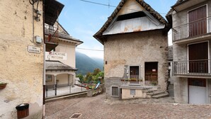 A cobblestone street with buildings, a sign for 'Elementare Materna,' and a visible entrance. - Apartment "Casa del Sole" with Mountain View & Wi-Fi (Toceno)