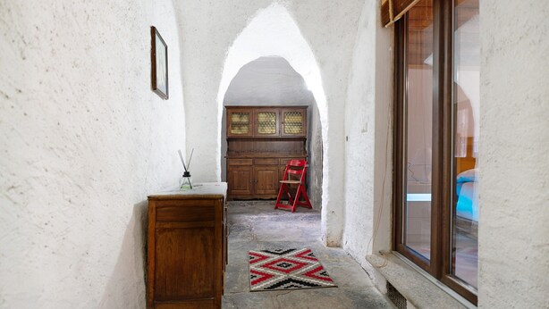 A narrow hallway with a wooden cabinet, a red chair, and a patterned rug. - Apartment "Casa del Sole" with Mountain View & Wi-Fi (Toceno)