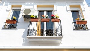 Un edificio con paredes exteriores blancas, techo de tejas y tres ventanas con barandillas de hierro forjado.