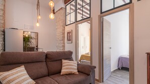 Un salón acogedor con un sofá marrón, una planta en maceta y una lámpara moderna.