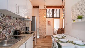 Una cocina moderna con salpicadero de azulejos, encimera de madera y un comedor con una mesa dispuesta para dos personas.