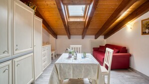 Ein Zimmer mit Oberlicht, einem Tisch mit Stühlen, einem roten Sofa und weißen Schränken.