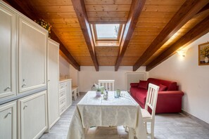 A room with a skylight, a table with chairs, a red sofa, and white cabinets. - Holiday Home "Le More - Casa Zara" with Shared Garden & Wi-Fi (Valfabbrica)