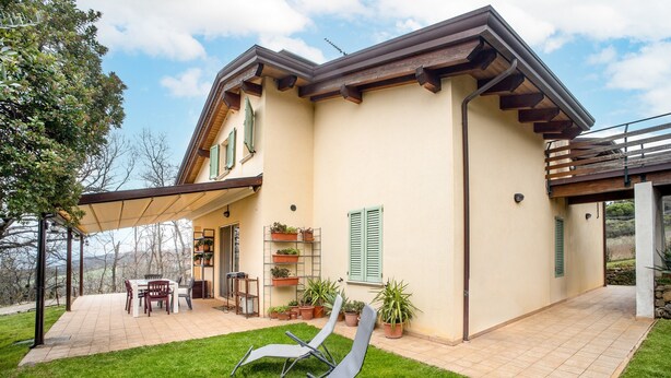 Ein Haus mit Terrasse, Gartenmöbeln und Blumentöpfen.