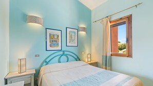 A bedroom with a bed, two wall-mounted lamps, a window with curtains, and two framed pictures on the wall. - Holiday Home 'Casa Erbì' with Sea View, Private Terrace and Private Garden (Torre dei Corsari Arbus)