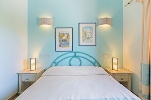 A bedroom with a bed, two bedside tables, two wall-mounted lamps, and two framed pictures. - Holiday Home 'Casa Erbì' with Sea View, Private Terrace and Private Garden (Torre dei Corsari Arbus)