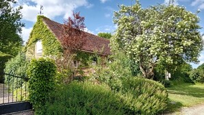 A historic building with ivy-covered walls, a traditional tiled roof, and a gravel path leading to a metal gate.