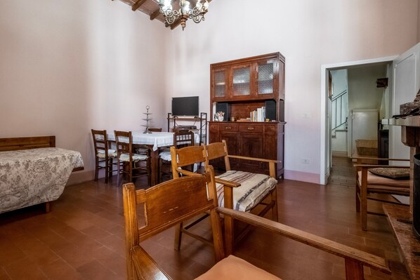 Une pièce comprenant un lit, des chaises en bois, une table à manger, un téléviseur et un meuble.