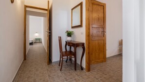 A hallway with a wooden door, a mirror, a small table with a plant, and a chair. - Apartment "La Sosta del Pellegrino" with Mountain View, Private Garden & Wi-Fi (Sorano)