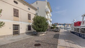 A cobblestone street with buildings, a tree, and a boat dock. - Apartment 'Al Porticciolo' with Sea View, Balcony and Air Conditioning (Grado)