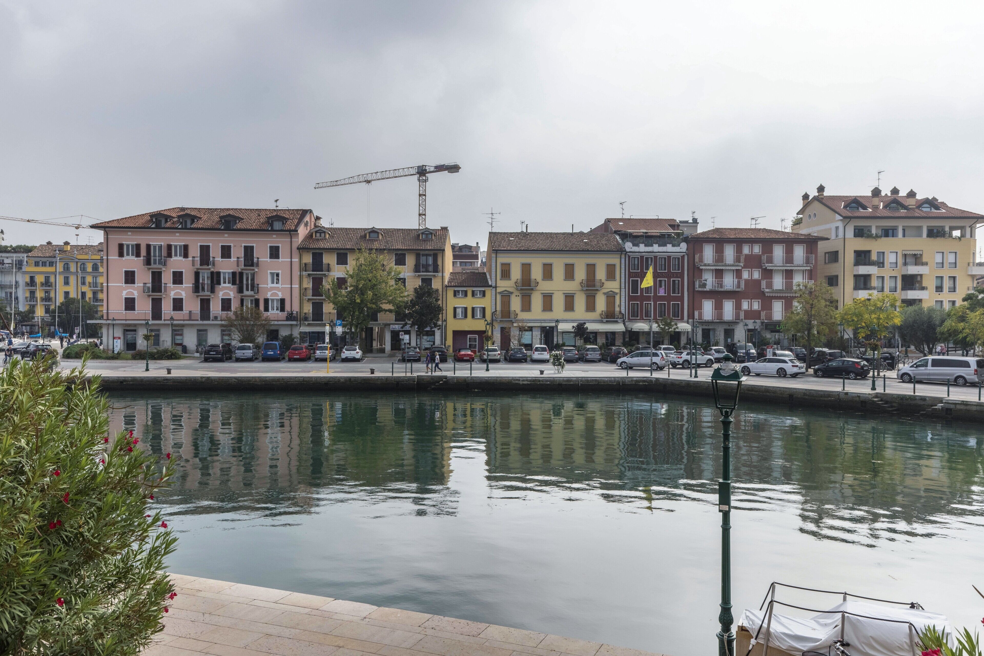 A waterfront view with multi-story buildings, a canal, and a construction crane.