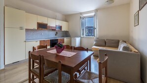 A compact living space with a dining area, kitchenette, and a sofa. - Apartment 'Al Porticciolo' with Sea View, Balcony and Air Conditioning (Grado)